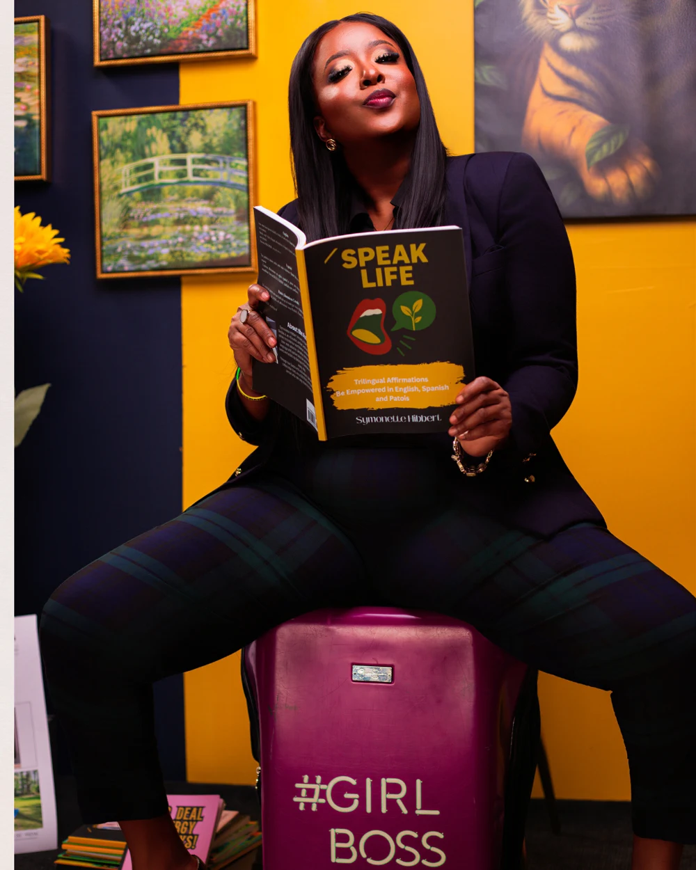 Symonette Hibbert in a black suit holding her book Speak Life
